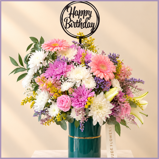Birthday Garden Charm arrangement with gerbera, roses, lily and colourful flowers in a teal vase